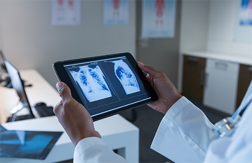 Mid section close-up of African-american female doctor examining x-ray on digital tablet in the hospital. Shot in real medical hospital with doctors nurses and surgeons in authentic setting